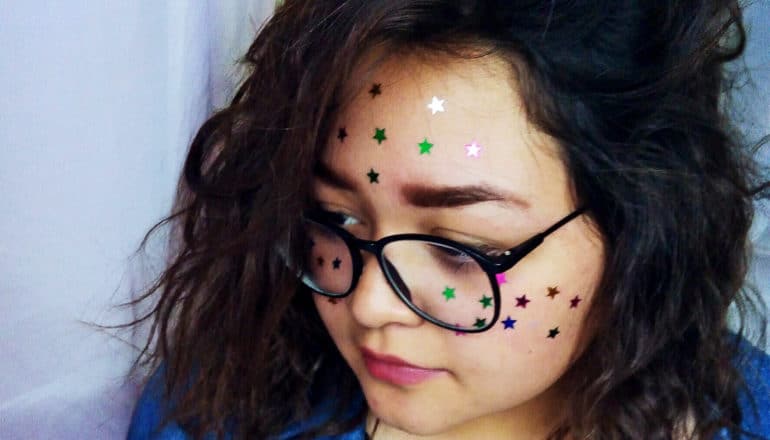 A young woman looks down with star stickers all over her face