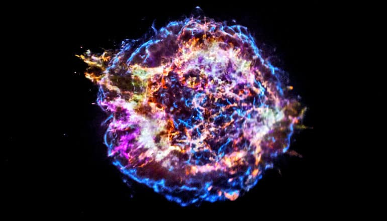 The supernova remnant looks like an explosion of purple, blue, and orange against the blackness of space