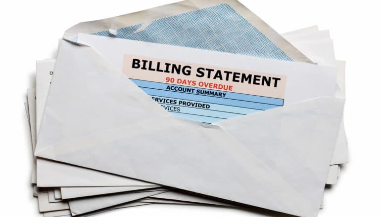 stack of envelopes with top one showing "billing statement 90 days past due"