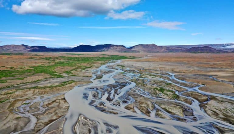 river plain in front of distant mountains, blue sky