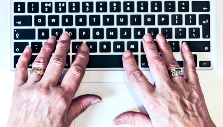 An older woman's hands on a laptop keybaord