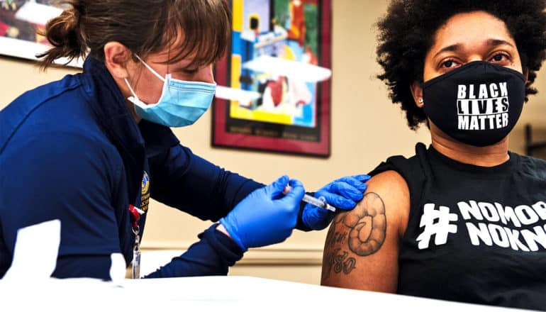 A young woman wearing a Black Lives Matter face mask gets a dose of the COVID-19 vaccine