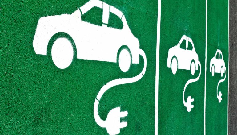 White electric car charging symbols in green parking spaces