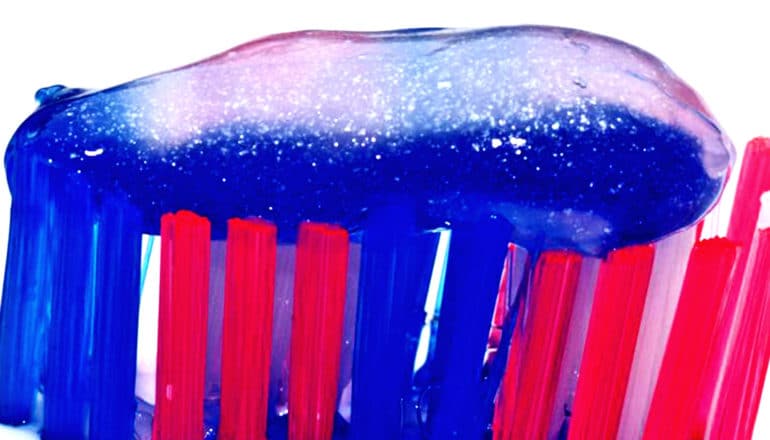 Toothpaste on a blue and pink toothbrush