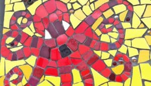 A mosaic shows an octopus in red tiles surrounded by yellow tiles