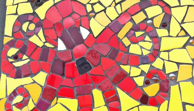 A mosaic shows an octopus in red tiles surrounded by yellow tiles