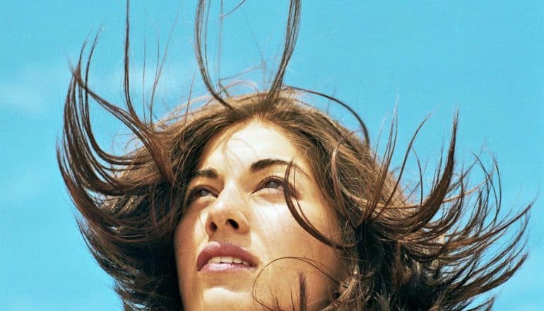 A woman looks off into the distance while her hair blows around