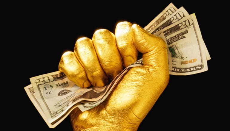 gold hand clutches $20 bills