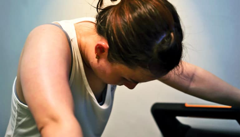 A winded woman leans down while exercising