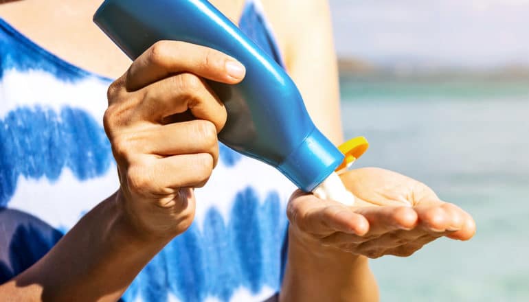 A woman squeezes sunscreen into her hand