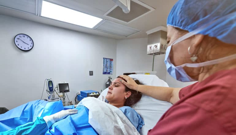 nurse puts hand on forehead of person in labor