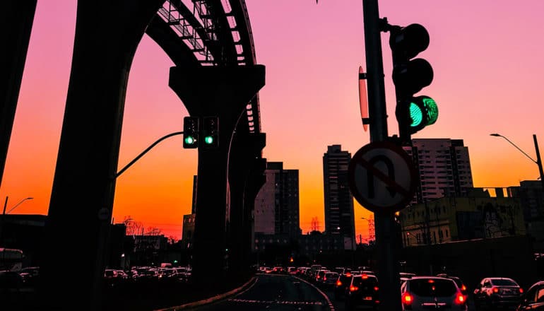 sunset behind traffic under bridge