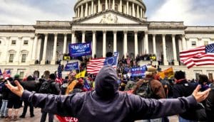 A man holds his arms up as he looks at the insurrectionist mob attack on the US Capitol building