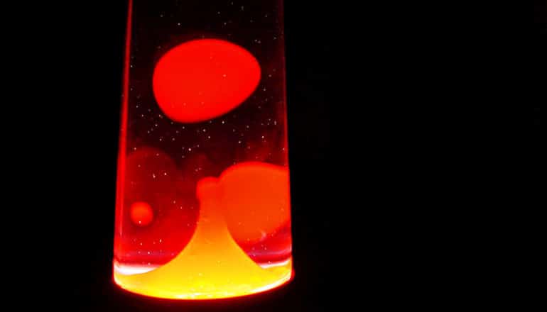 A red lava lamp with large bubbles in it on a black background