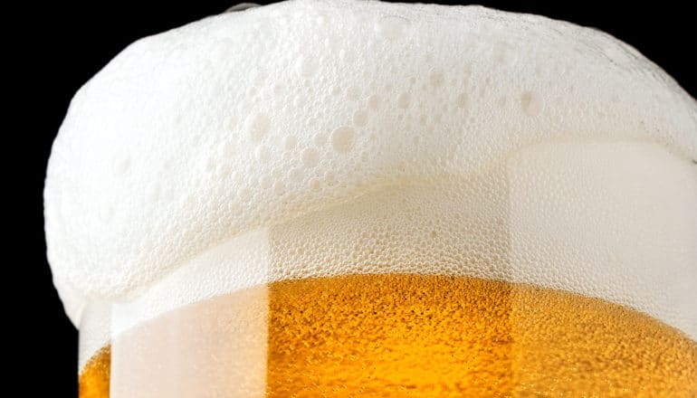 A glass of beer overflowing with foam