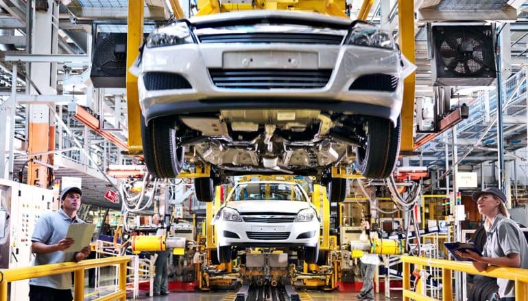 Cars on an assembly line with workers examining them