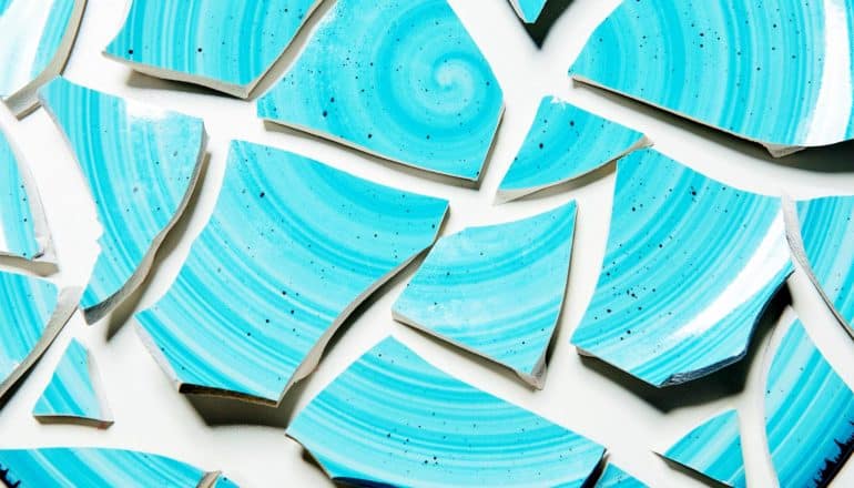 Pieces of a blue ceramic plate on a white background