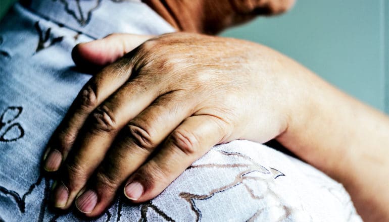 A woman holds her shoulder in pain