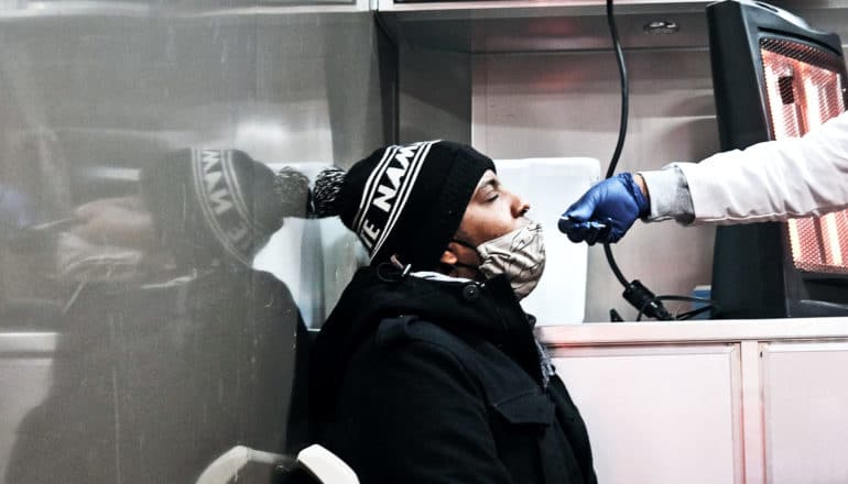 A man leans his head back to get a COVID-19 nasal swab test