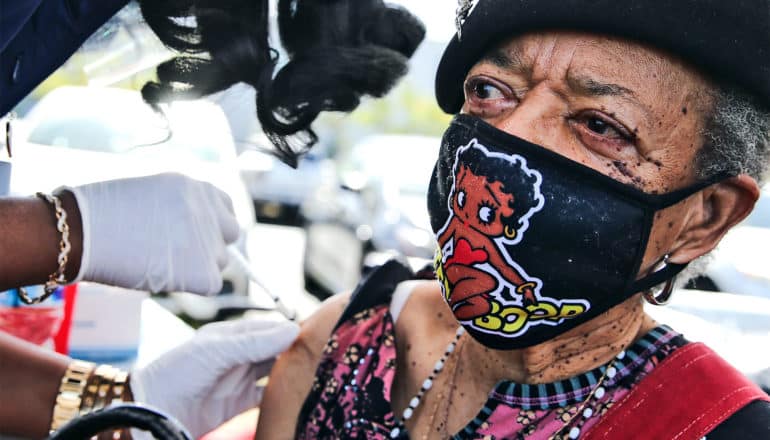 A woman wearing a Betty Boop face mask gets a COVID-19 vaccine