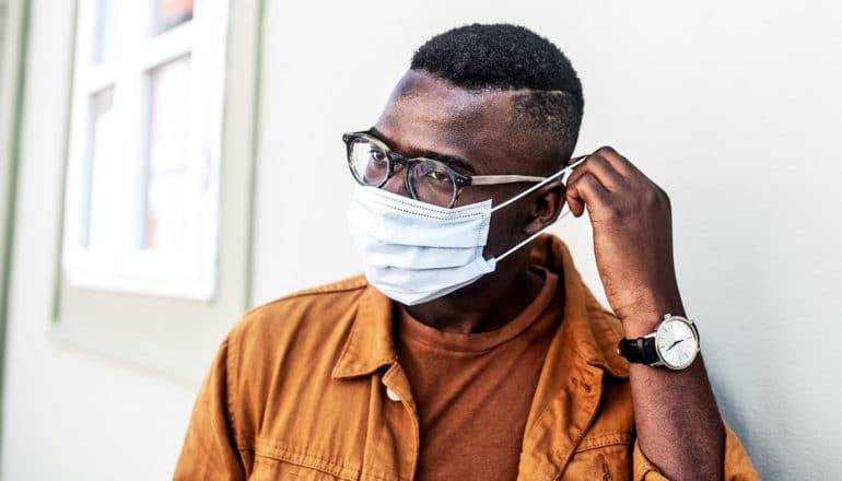 A man fixes his mask's ear strap