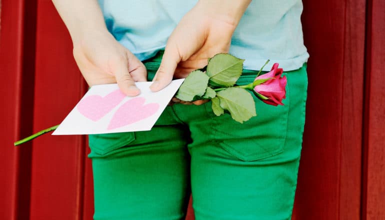 hands hold valentine and rose behind back for first impression