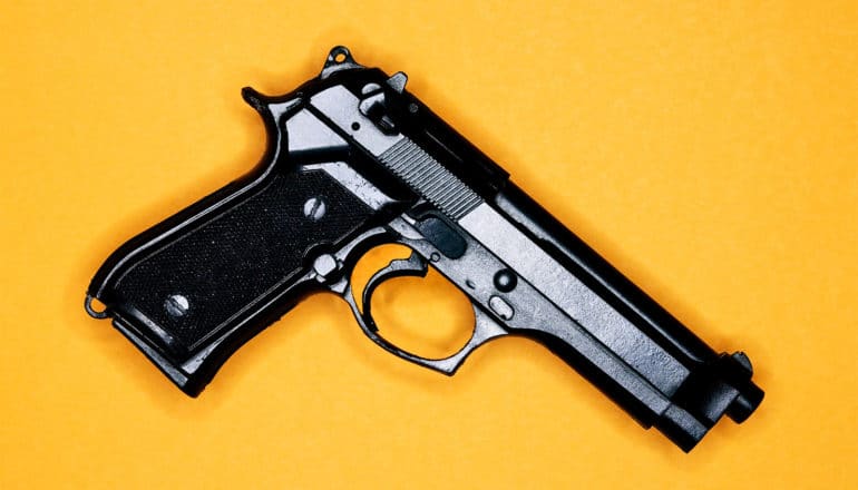 A handgun on a yellow background