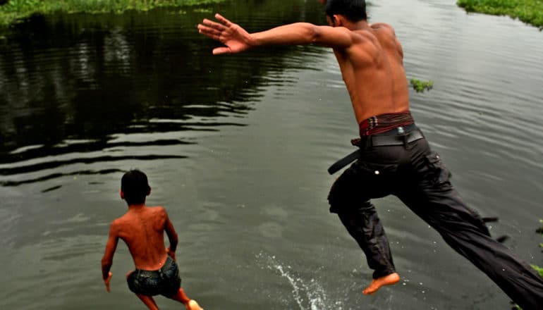 two boys/men jump in water