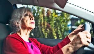 An older woman looks in her rear view mirror while driving