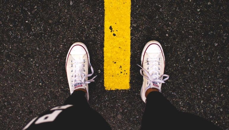 high angle view of sneakers on either side of yellow line on street