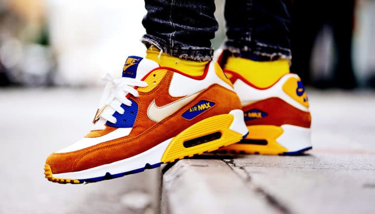 A man steps off a curb wearing brightly colored sneakers