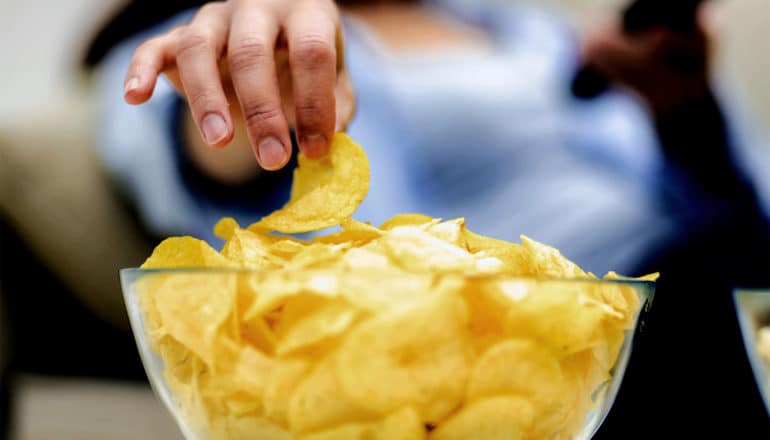 A woman grabs a potato chip from a bowl