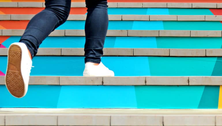 A teen runs up colorful stairs