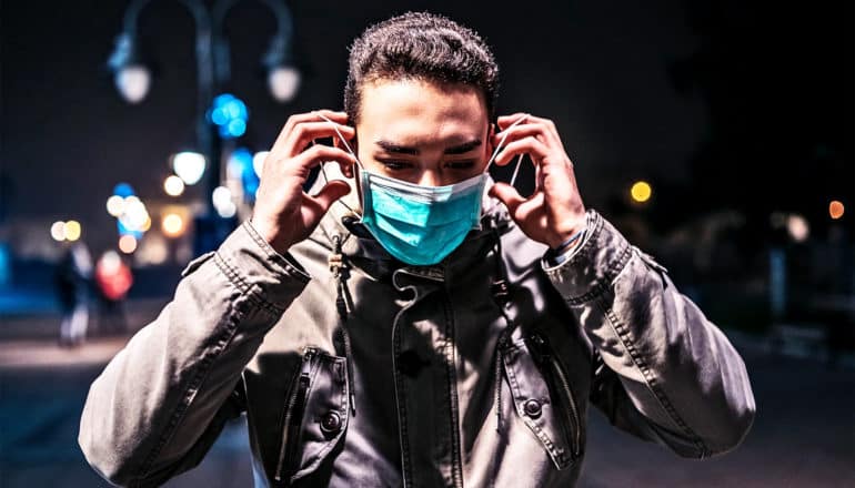 A young man puts on a face mask