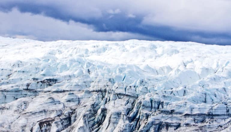 The Greenland ice sheet stretches out underneath a blue sky