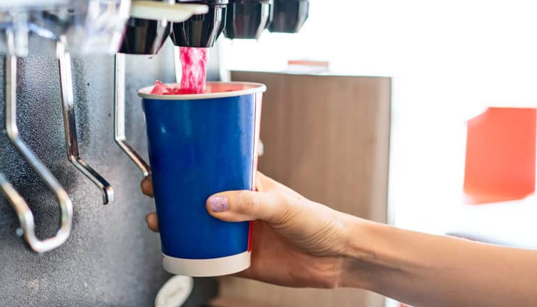 A person fills a cup of soda at a fountain