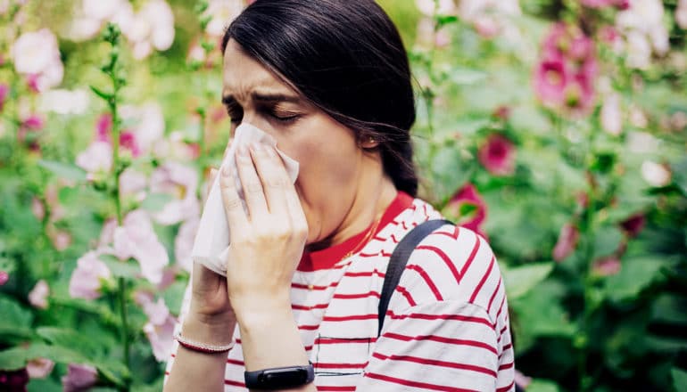 A young woman sneezes into tissue