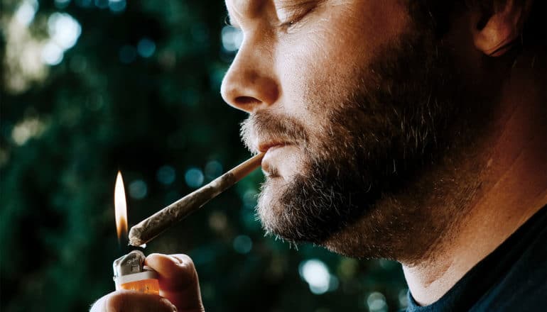 A man lights a joint in profile