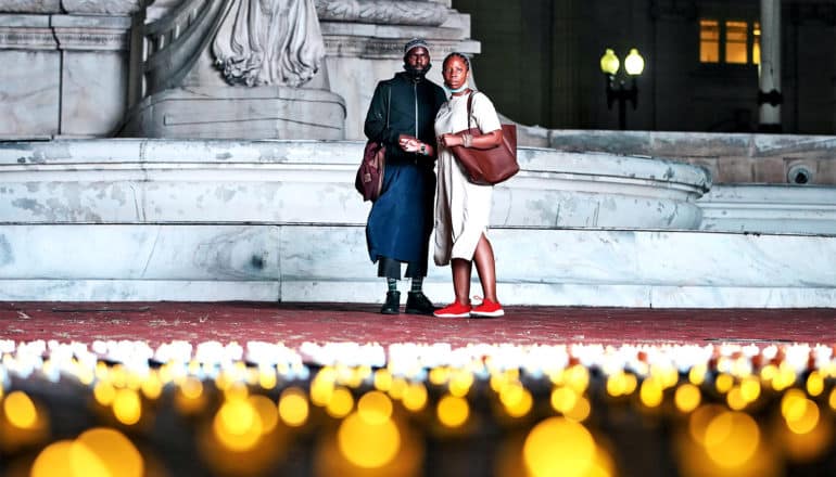 A couple stares out at a field of candle lights