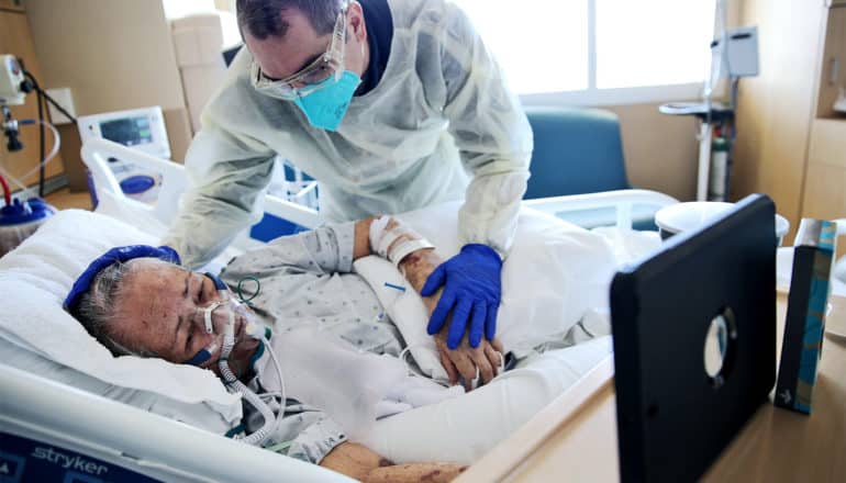 A chaplain comforts a COVID-19 patient in the hospital