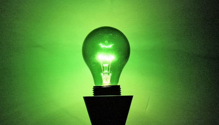 A green lightbulb shining in a dark room