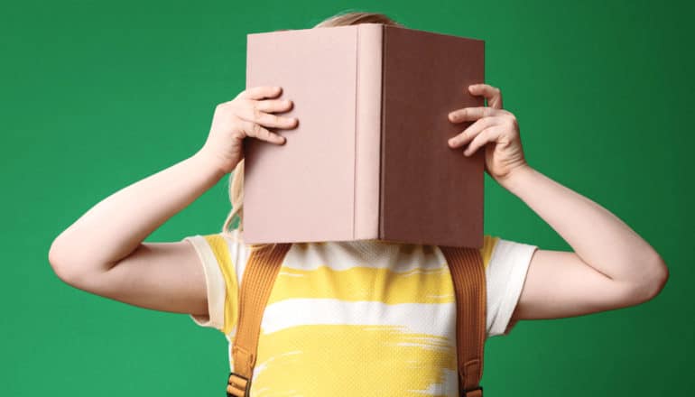 kid holds book in front of face