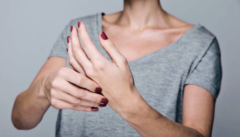 A woman holds one hand with her other