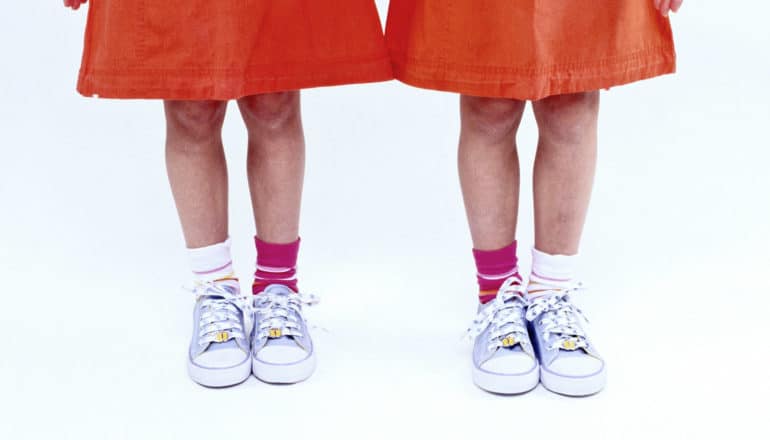 Two twin girls in red dresses on a white background