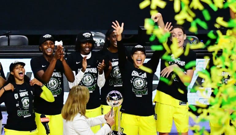 group of athletes celebrate, confetti in foreground