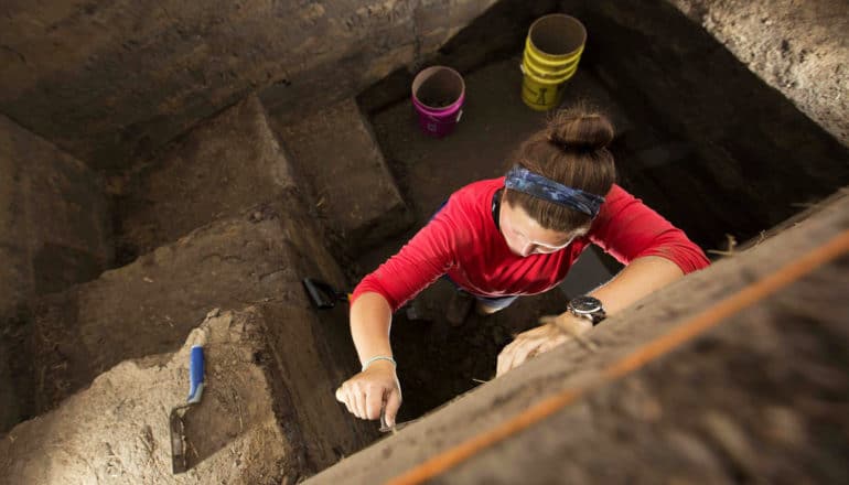 person uses tools in dirt trench