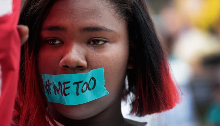 person with #MeToo written on blue tape across mouth