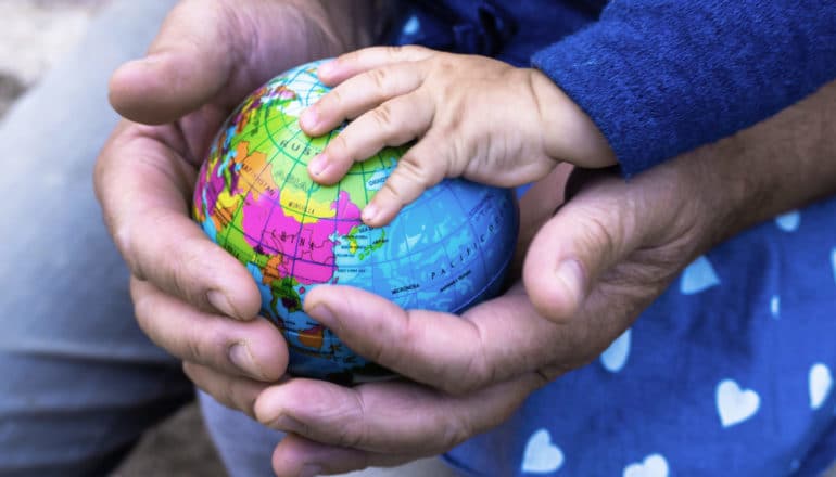 small globe in adult and baby hands