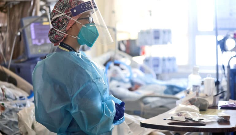 A health worker looks over several covid-19 patients in hospital beds