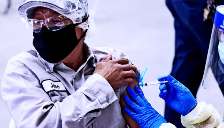 A man rolls up his sleeve to get a COVID-19 vaccine